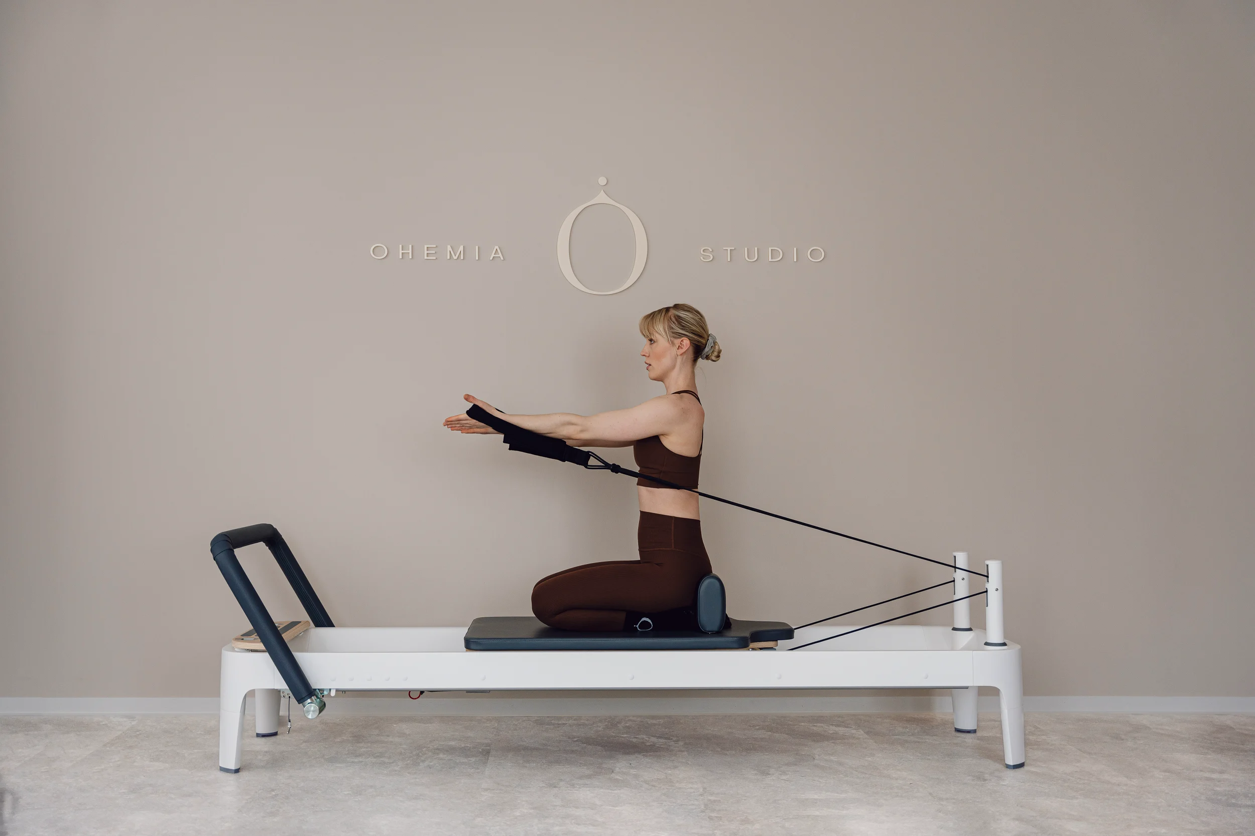 Valerie Mack auf einem Reformer Gerät im Kurs Reformer Foundation, sie demonstriert die Basics von Pilates Reformer im OHEMIA Studio in Stuttgart