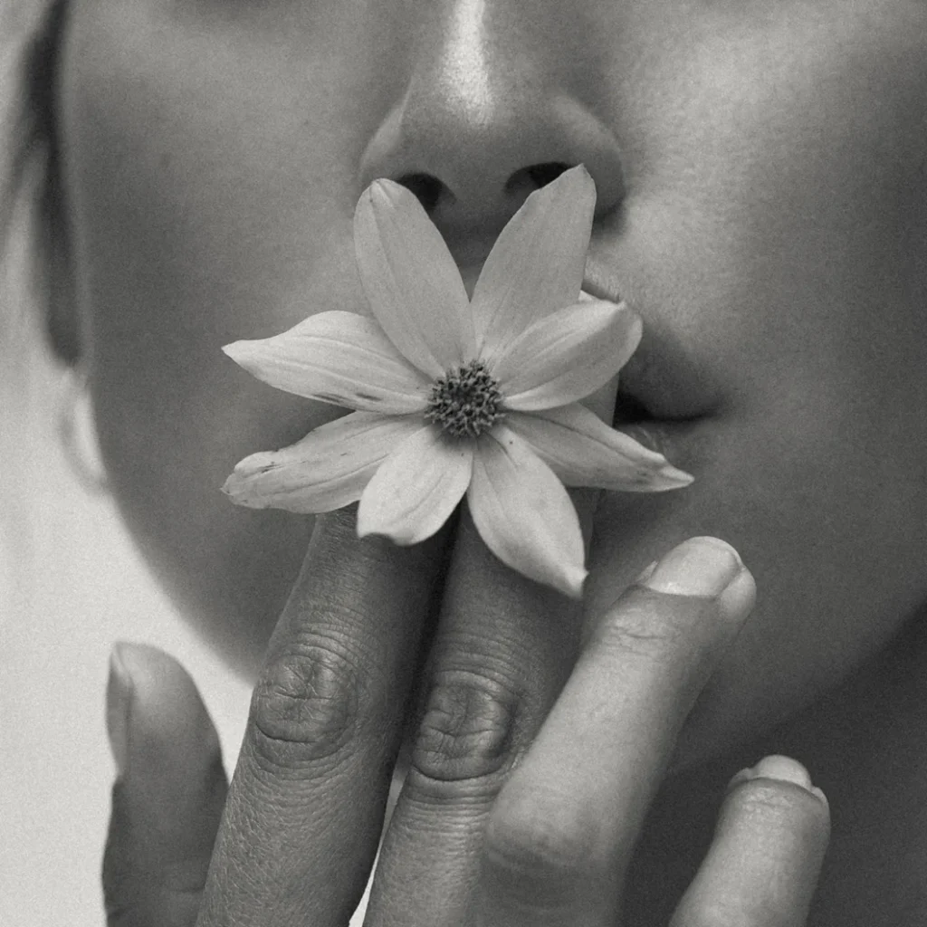 Junge Frau mit Blüte an den Lippen als Sinnbild für ein harmonisches und respektvolles Miteinander im OHEMIA Studio – Yoga, Pilates und Reformer in der Stuttgarter Innenstadt