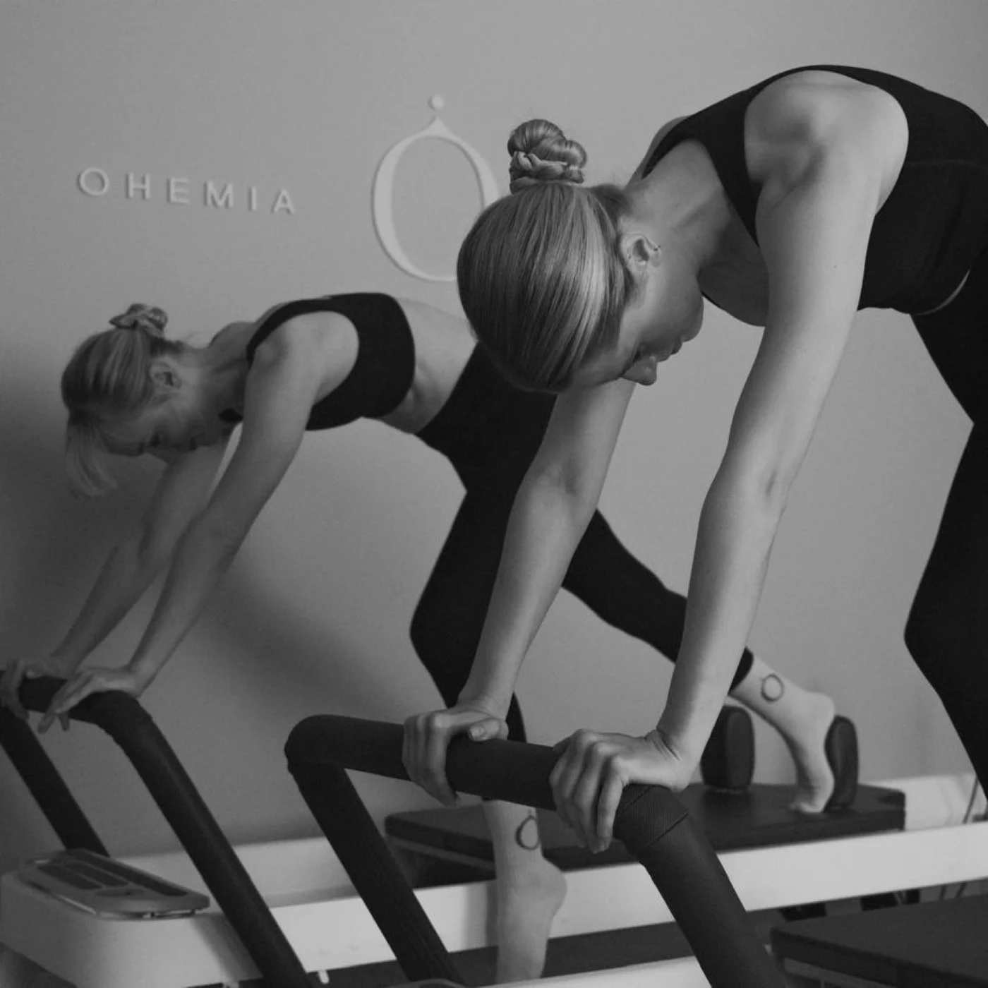 Zwei junge Frauen auf Reformer Geräten im Pilates Reformer Kurs von OHEMIA